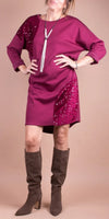 Woman wearing a magenta sequin-accented dress with long sleeves and knee-high suede boots