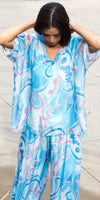 Woman wearing loose blue and pink swirl print silk blouse and matching pants outdoors