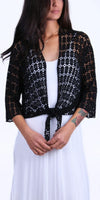 Woman wearing a black crochet knit tie-front cardigan over a white dress
