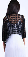 Woman wearing black crochet lace shrug over white dress, back view