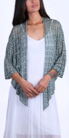 Woman wearing a light green crochet knit cardigan over a white dress