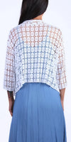 Back view of a woman wearing a white crochet lace cardigan over a blue dress