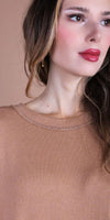 Close-up of woman wearing a light brown knit top with subtle stitching detail