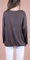 Back view of woman wearing a loose long sleeve brown top and white textured pants