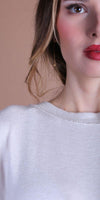 Close-up of woman in a light knit top with natural makeup and gold earring