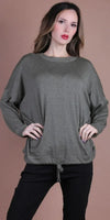 Woman wearing an olive green knit sweater with drawstring hem and black pants