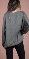 Back view of woman wearing loose long sleeve olive green top and black pants