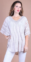 Woman wearing a loose white lace top with intricate patterns and white pants