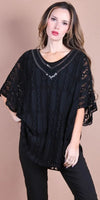 Woman wearing a black lace knit top with sequin V-neck and loose sleeves, paired with black pants