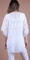 Woman wearing a white lace tunic top with geometric patterns, back view