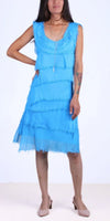 Woman wearing a sleeveless blue fringed dress with layered details and nude heels