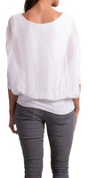 Back view of woman in white sheer blouse and grey pants