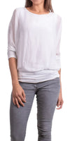 Woman wearing a loose white long-sleeve blouse with grey pants