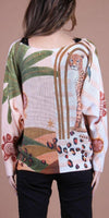 Woman wearing a sweater with cheetah print and abstract jungle pattern on the back.