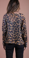 Woman wearing a leopard print long sleeve blouse with black pants, back view
