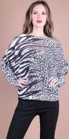 Woman wearing black and white animal print dolman sleeve blouse and black pants