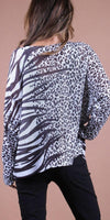 Woman wearing loose animal print knit sweater with black pants, back view