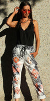 Woman in black lace tank top and patterned drawstring pants with orange sunglasses