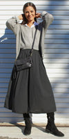 Woman in a grey sweater, black maxi skirt, tall black boots, and black crossbody bag