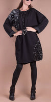 Woman wearing a black sequin-embellished sweater dress with leggings and ankle boots