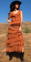 Woman in rustic orange tiered maxi dress, silver concho belt, and black cowboy hat outdoors