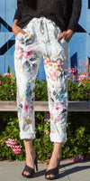 Woman wearing white floral print pants with drawstring waist and rolled cuffs, paired with black heels