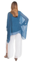 Woman wearing sheer blue silk poncho top and white linen wide-leg pants