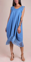 Woman wearing a blue sleeveless linen dress with lace shoulder detail and ruffled hem