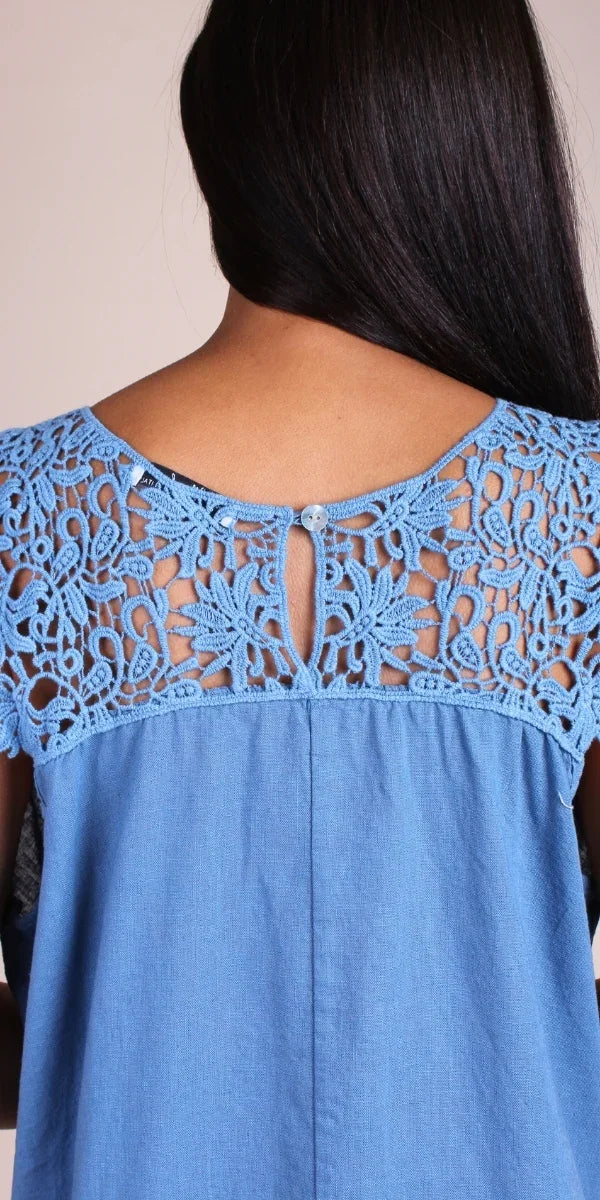 Back view of woman wearing blue linen top with crochet lace yoke and button closure