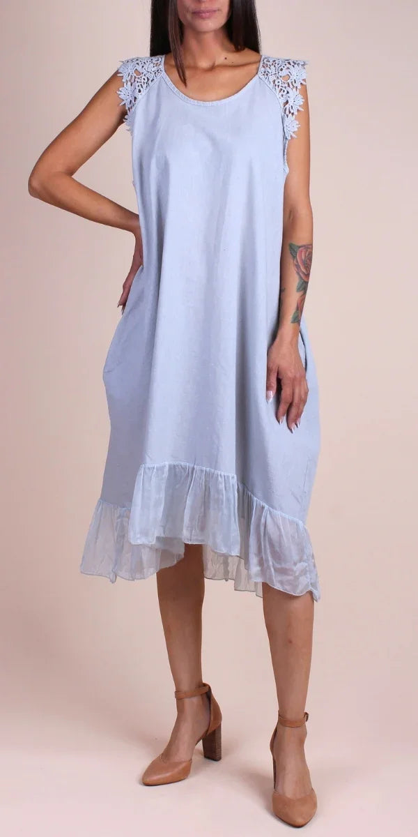 Light blue linen sleeveless dress with lace shoulders and ruffled hem, modeled indoors