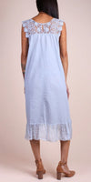 Back view of woman in light blue linen midi dress with lace yoke and ruffled hem