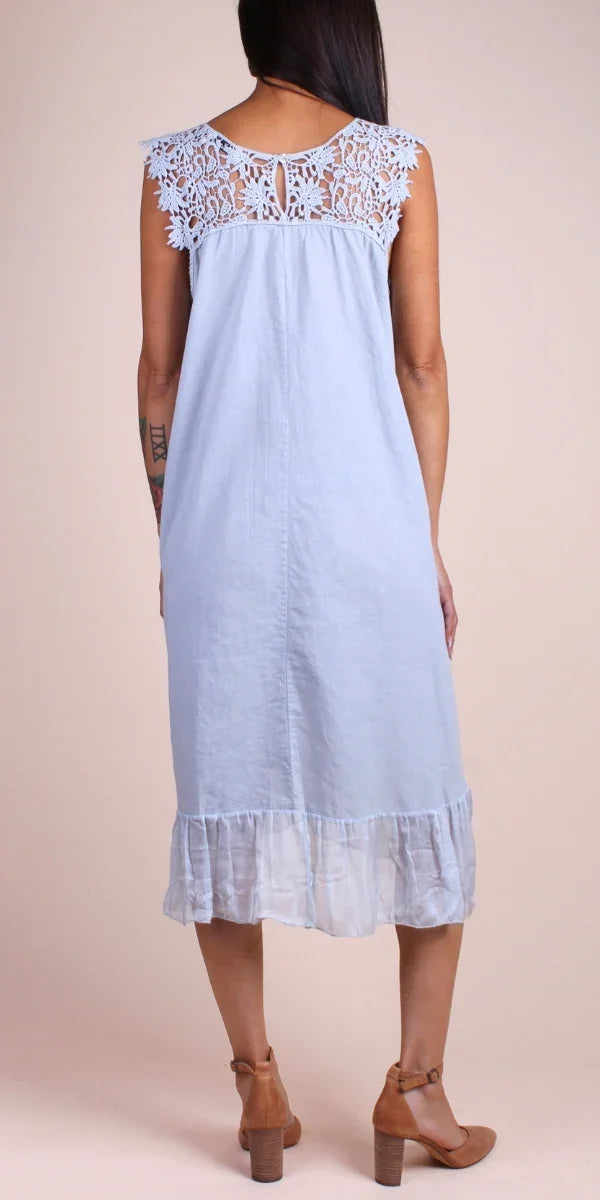 Back view of woman in light blue linen midi dress with lace yoke and ruffled hem
