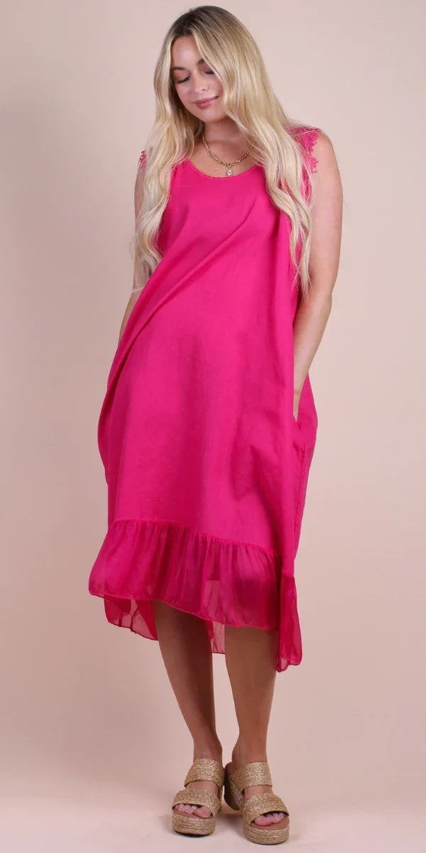 Woman wearing a sleeveless hot pink linen dress with lace accents and ruffled hem