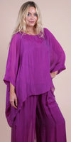 Woman wearing a flowy purple silk blouse with matching wide-leg pants, fashion outfit