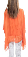 Back view of woman wearing a sheer orange poncho top and white script print pants