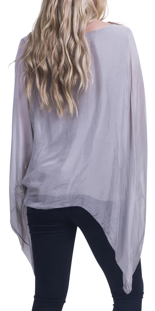 Back view of woman wearing light grey sheer silk blouse with batwing sleeves and black pants