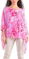 Woman wearing a flowy pink and purple animal print blouse with white pants