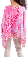 Woman wearing sheer pink animal print poncho top with light pants, photographed from the back