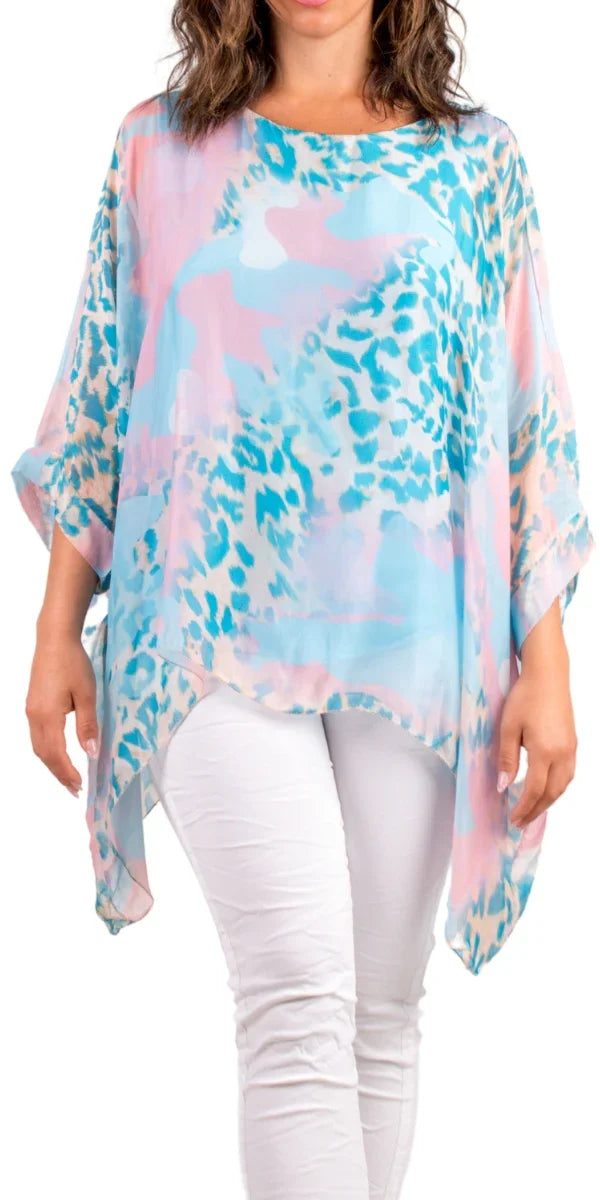 Woman wearing a flowy pastel animal print sheer top with white pants