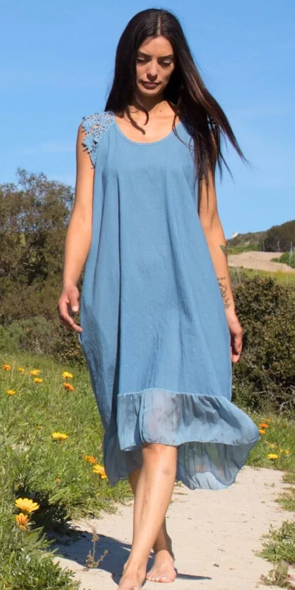 Woman in blue sleeveless dress with lace shoulder detail walking outdoors on a sunny day