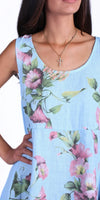 Light blue sleeveless dress with pink floral print, worn by a woman with a gold cross necklace