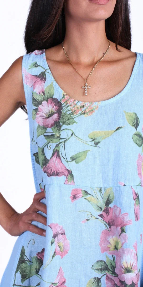 Light blue sleeveless dress with pink floral print, worn by a woman with a gold cross necklace