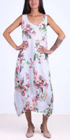 Woman wearing sleeveless white floral linen dress with pink and green flower print