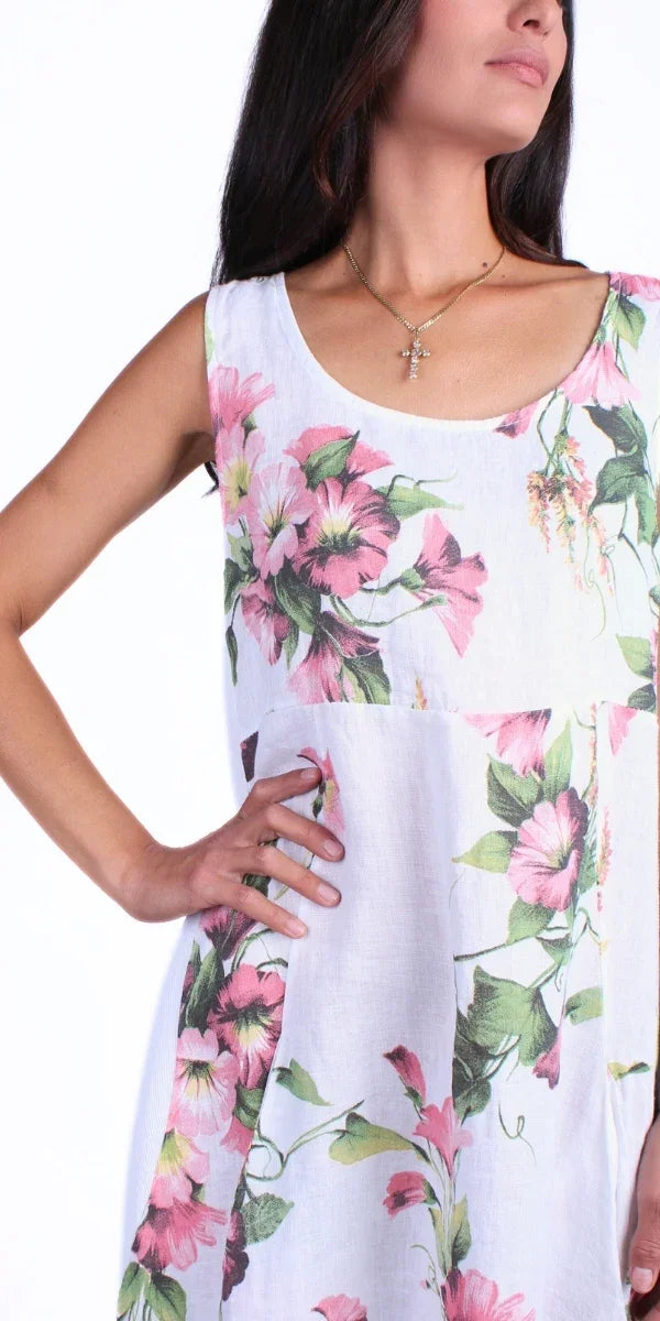 Woman wearing sleeveless white linen dress with pink floral print and scoop neckline
