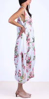 Woman wearing sleeveless white floral linen dress with pink flowers, side view
