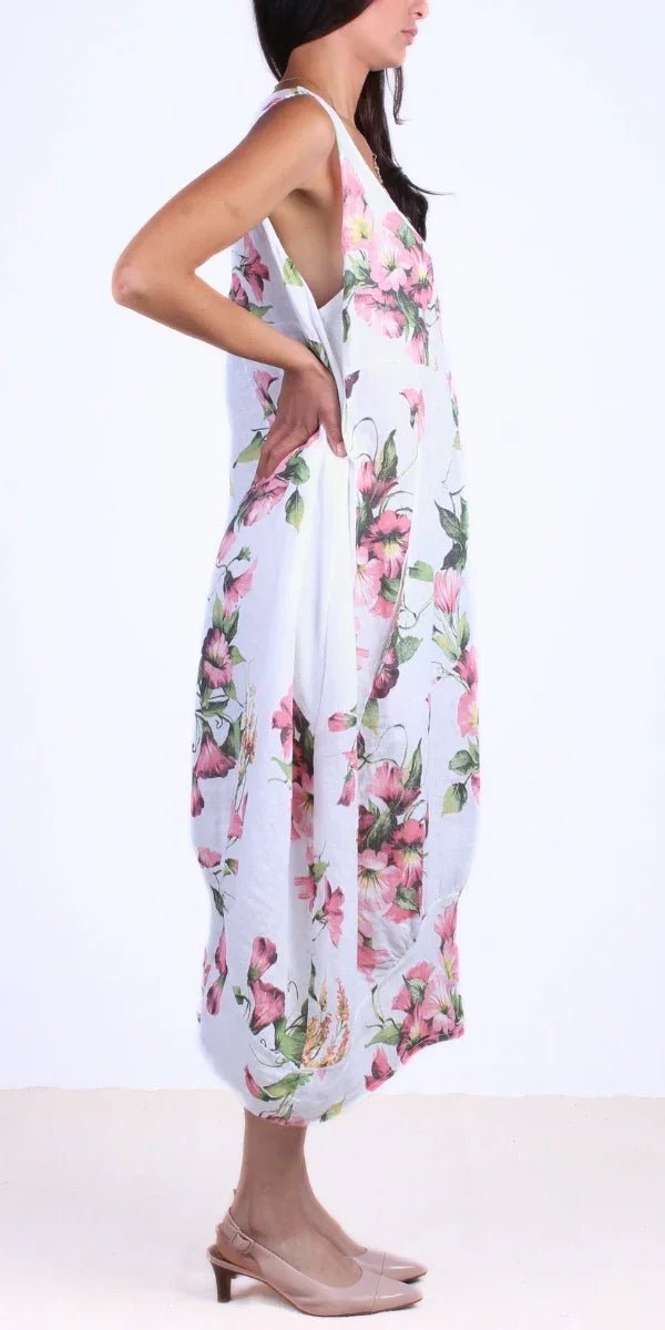 Woman wearing sleeveless white floral linen dress with pink flowers, side view