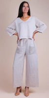 Woman wearing a beige linen two-piece set with crochet sleeves and pocket details