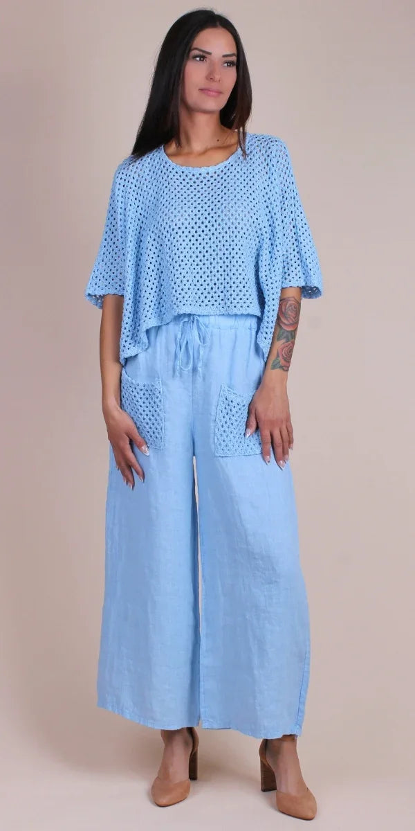 Woman in light blue crochet top and wide leg linen pants with front pockets