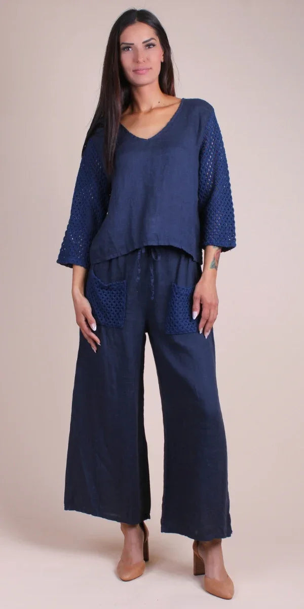 Woman wearing navy blue linen wide-leg pants and crochet sleeve top, front view
