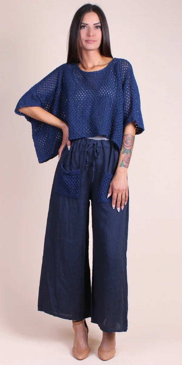 Woman wearing navy crochet knit top with matching wide-leg linen pants and nude heels